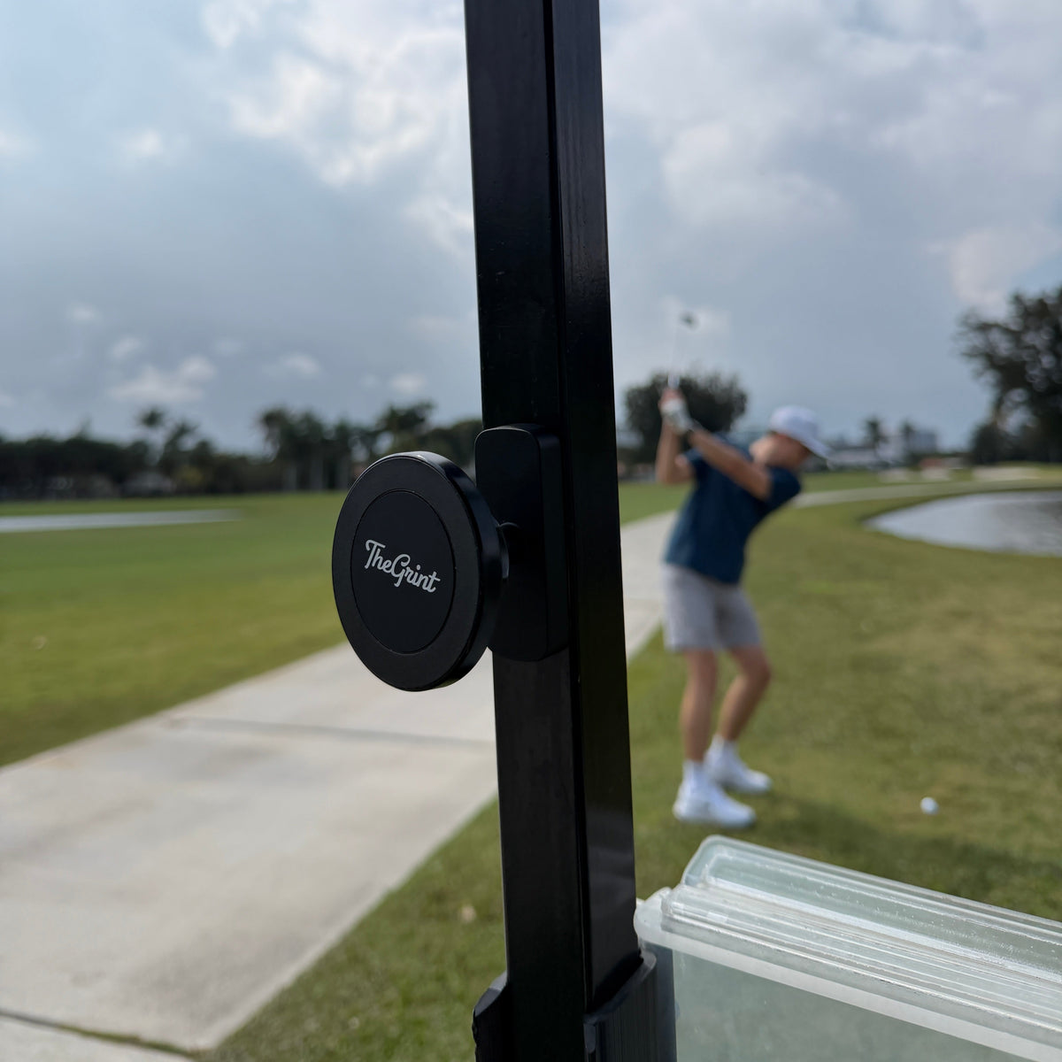 Golf cart with 'TheGrint' device on a golf course, person in the background