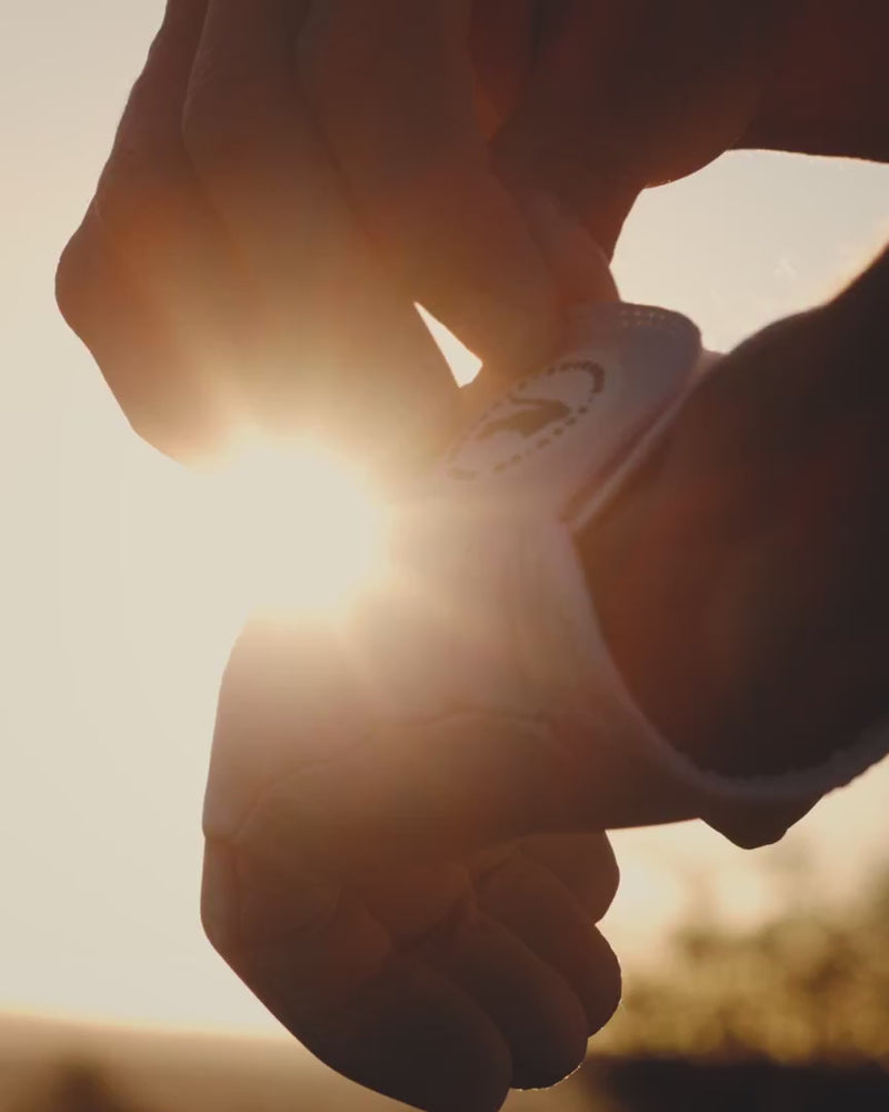 Golfer pulling on a glove at sunrise