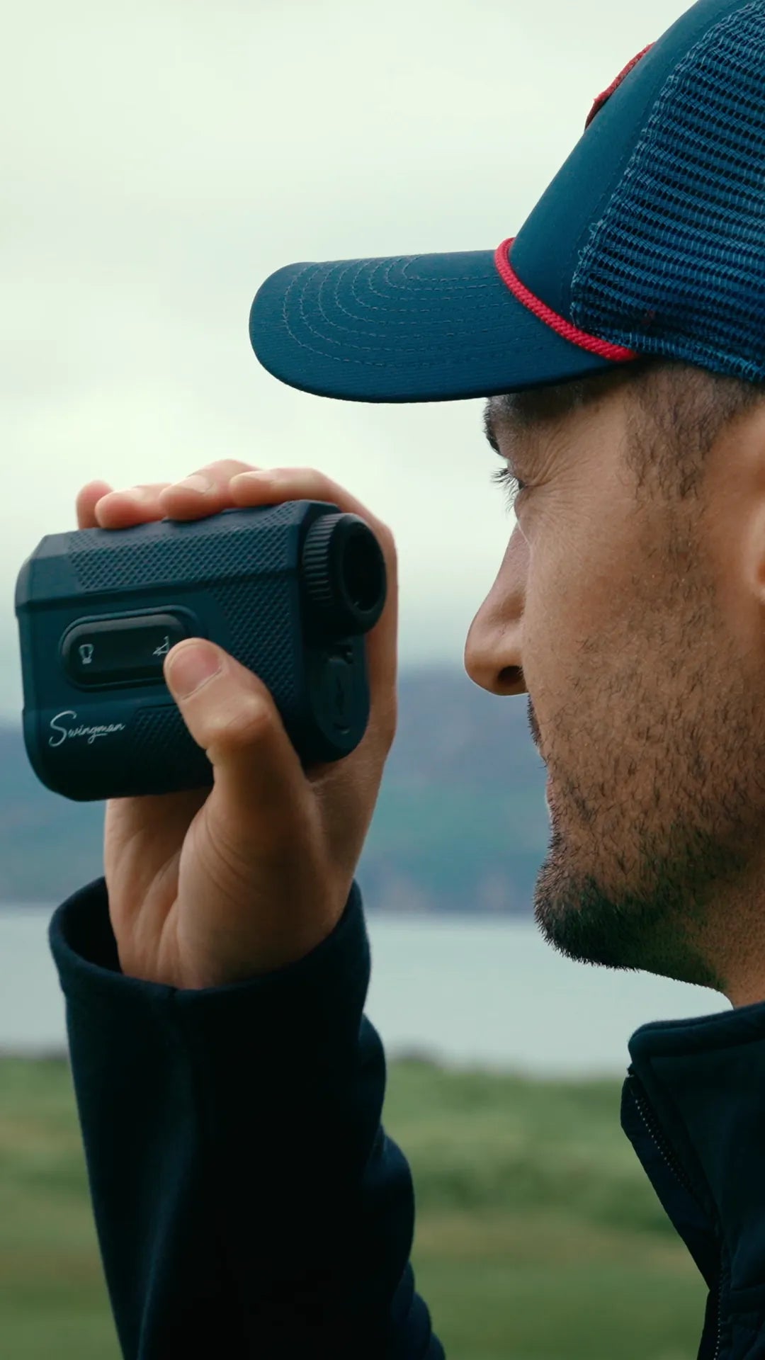 Golfer ranging the flag with the Swingman Classic Rangefinder on a links course by the sea